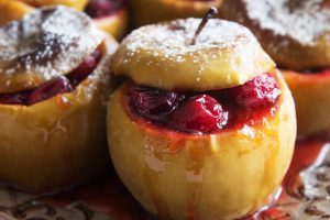 Horizontal photo of baked apples with cranberries and sugar powder